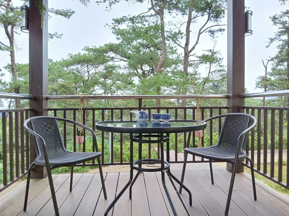 A terrace with a small table and two chairs looking out over pine trees at the A&J e-Edu Academy campus in Baguio